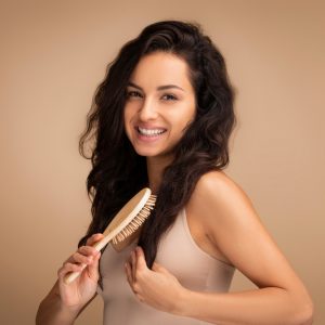 femeie tanara utilizeaza o perie de par